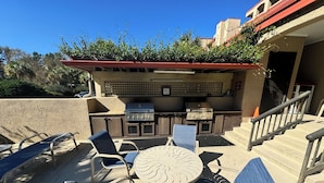 An outdoor patio with a grill, seating, and a view of the surrounding area.
