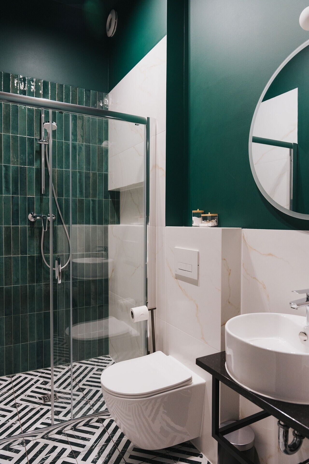 Un baño moderno con cabina de ducha de vidrio, inodoro y dos lavabos.