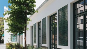 A modern building with large windows and a well-maintained garden.