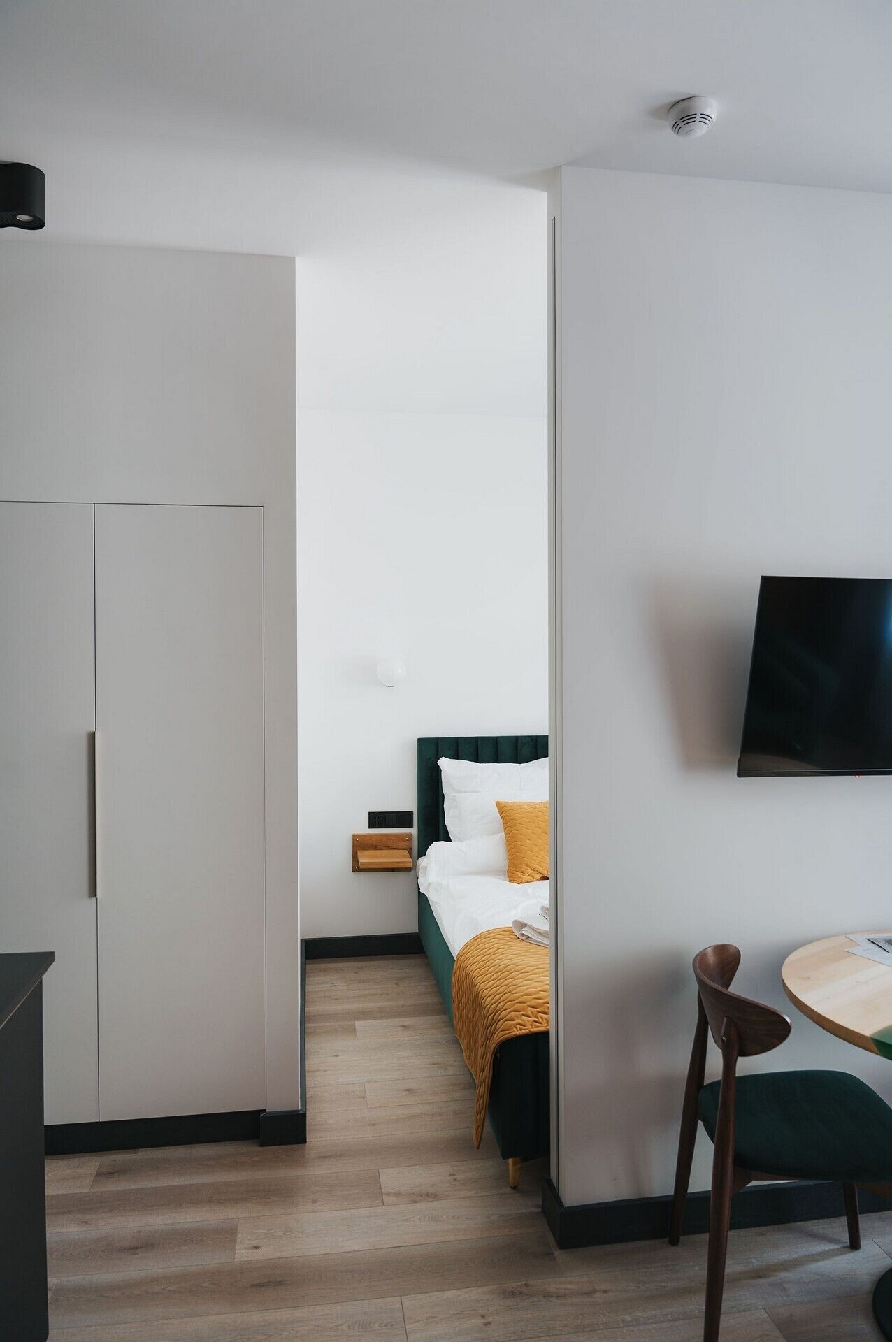 Ein Hotelzimmer mit Bett, Wandfernseher, Schreibtisch mit Stuhl und Kleiderschrank.