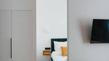 Ein Hotelzimmer mit Bett, Wandfernseher, Schreibtisch mit Stuhl und Kleiderschrank.