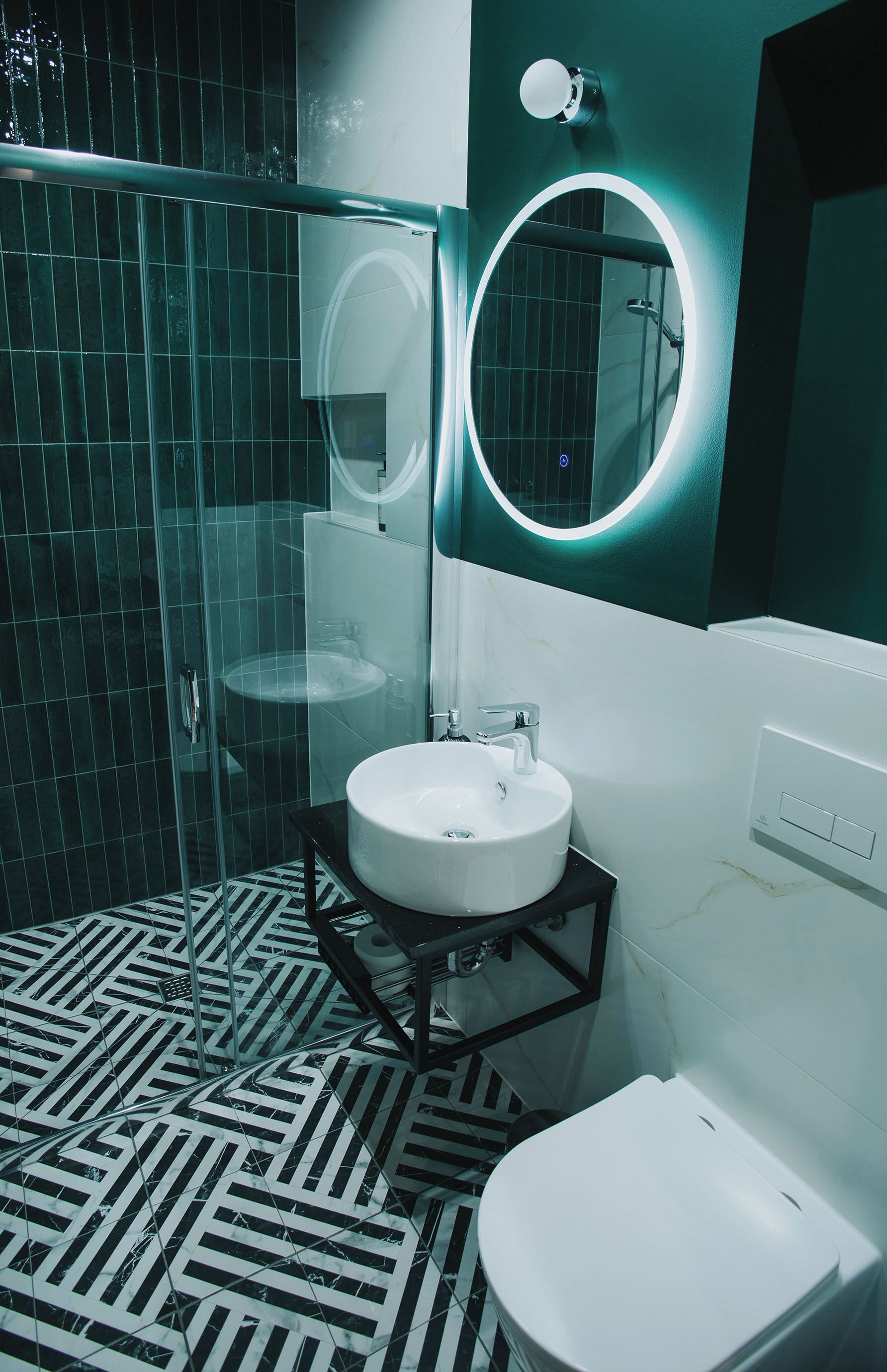 A modern bathroom with a glass shower enclosure, a white sink, and a toilet.