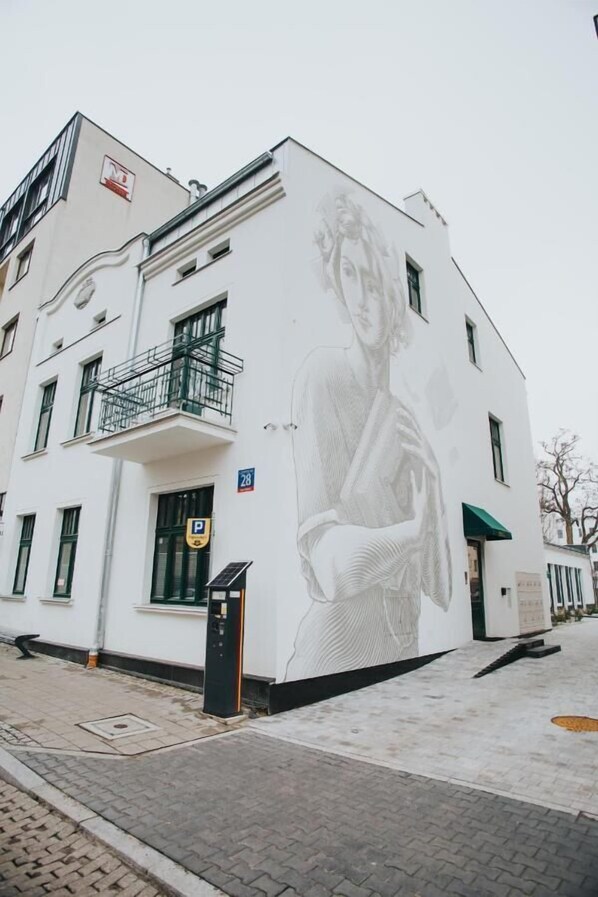A building with a large mural of a woman on its side, a parking sign, and a solar panel on the roof.