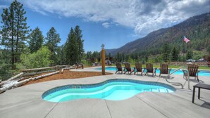 A swimming pool with a wavy edge, surrounded by wooden chairs and a flag. - High Mountain Home | AC, Pool, Hot Tub, Golf & Ski (Durango)