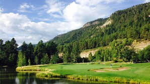 A golf course with a lake, surrounded by dense forest and hills. - High Mountain Home | AC, Pool, Hot Tub, Golf & Ski (Durango)