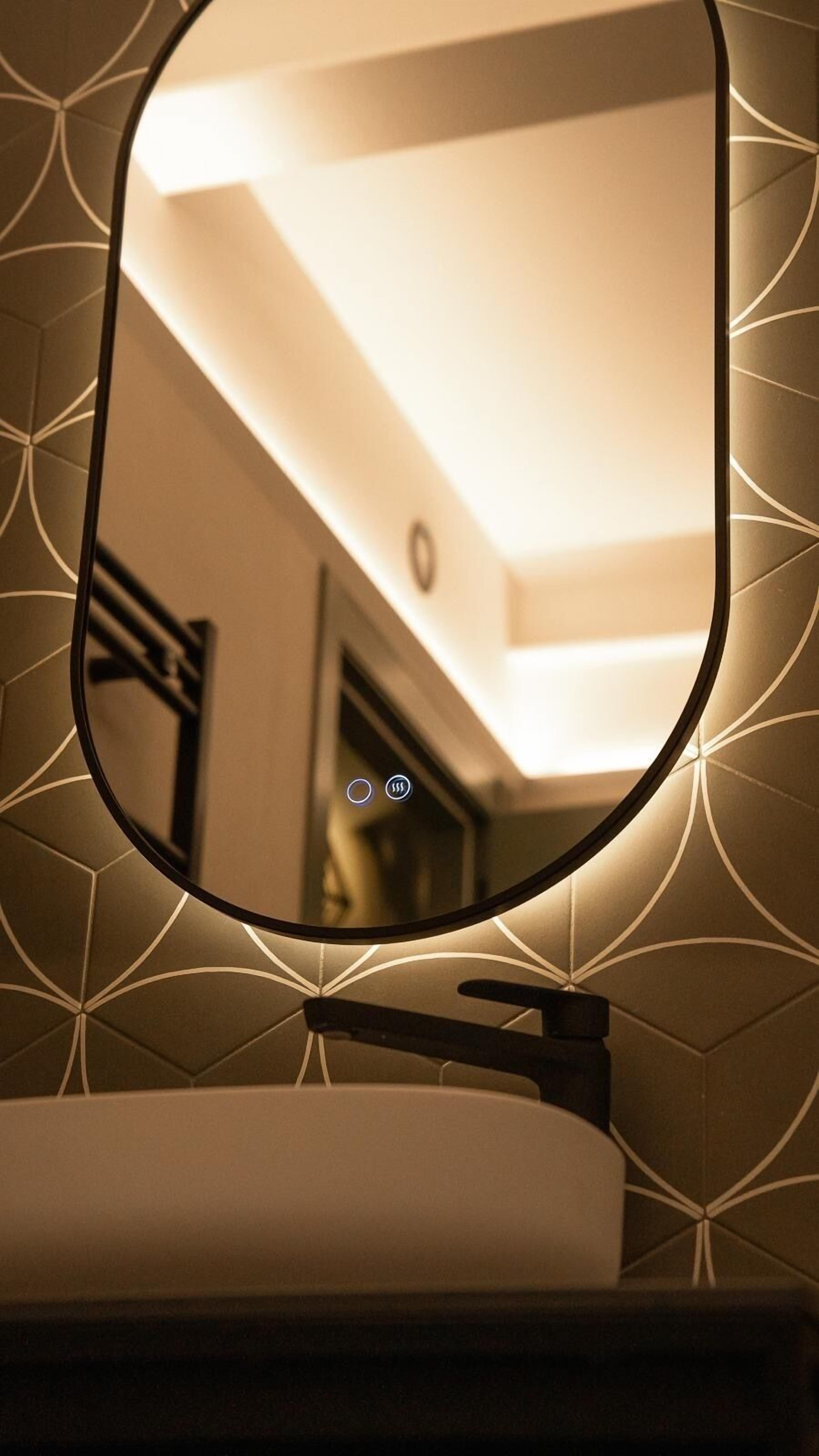 A bathroom with a mirror reflecting a ceiling light fixture and a door.