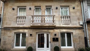 A stone building with a central entrance, two potted plants on either side, and a sign above the door. - INTRAMUROS Quiet Apartments (Muros)