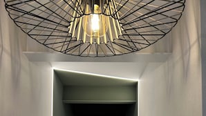 A modern hallway with a geometric light fixture, a door at the end, and a clean, minimalist design. - INTRAMUROS Quiet Apartments (Muros)