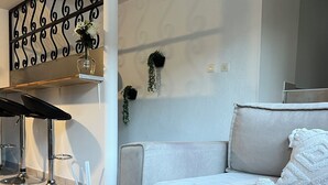 A modern living room with a sofa, a coffee table with a bottle of amber & sandalwood candle, and a decorative metal partition. - Beautiful T3 bis duplex near town center (Sens)
