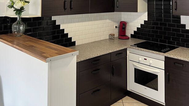 A modern kitchen with dark wooden cabinets, white countertops, a built-in oven, and a red coffee maker. - Beautiful T3 bis duplex near town center (Sens)
