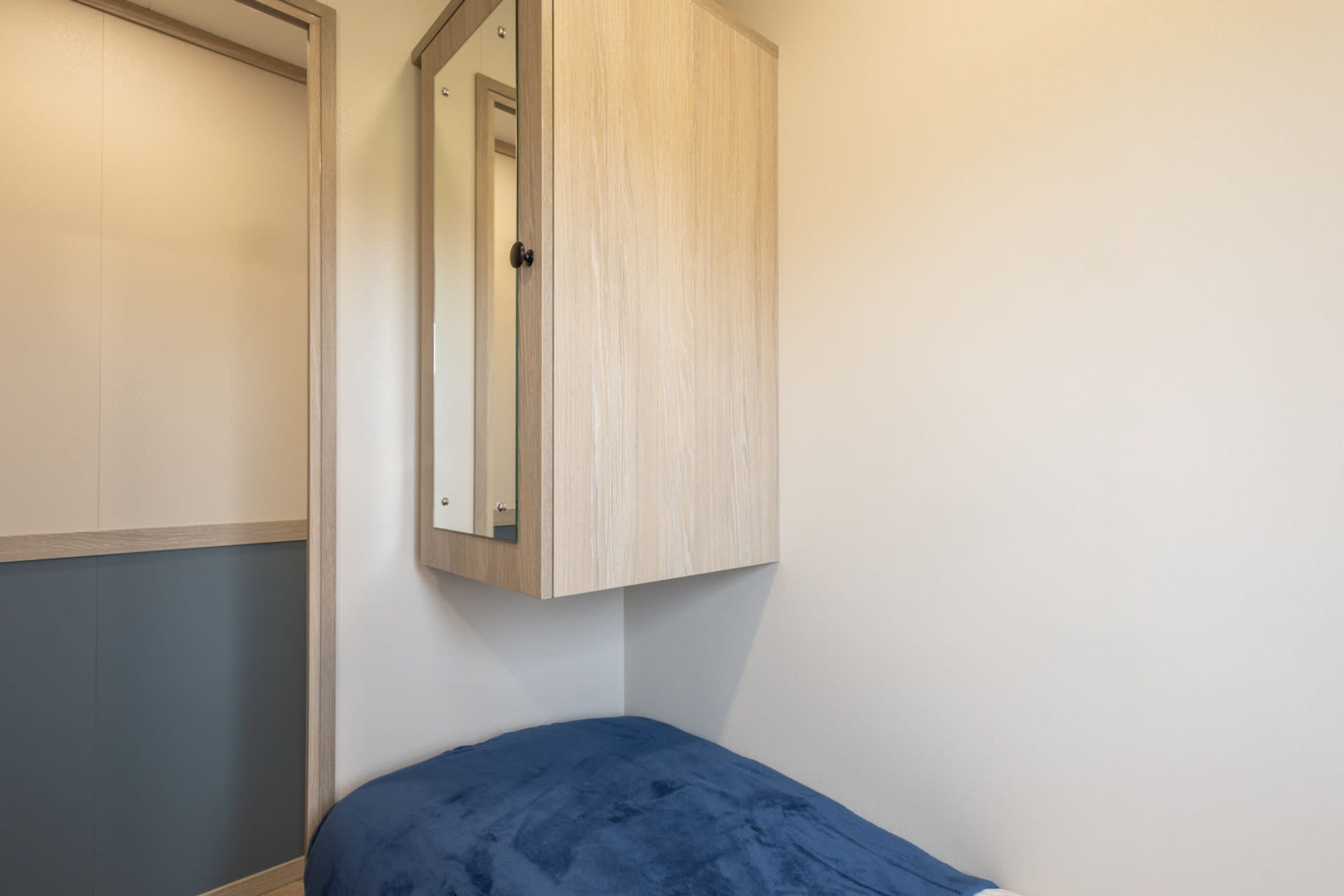 A bedroom with a bed, a wardrobe, and a mirror.