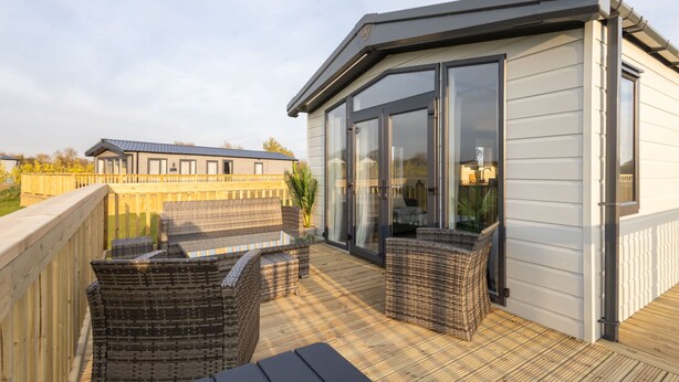 A covered outdoor deck with wicker furniture and a glass door leading to a room. - Host Stay Riverwood Ashdown Retreat (Pickering)