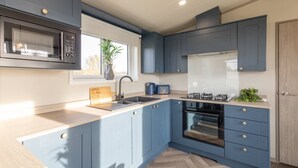 A modern kitchen with blue cabinets, a microwave, a sink, and a stove. - Host Stay Riverwood Ashdown Retreat (Pickering)