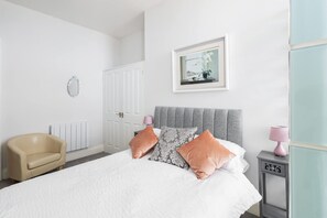A bedroom with a bed, a chair, a bedside table, a lamp, and a framed picture on the wall. - Host Stay Egton Bridge at the Sandbeck (Whitby)