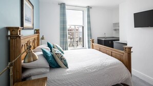 A bedroom with a large bed, a bedside table, a lamp, a TV, and a view of the outside. - Host Stay Grosmont at the Sandbeck (Whitby)