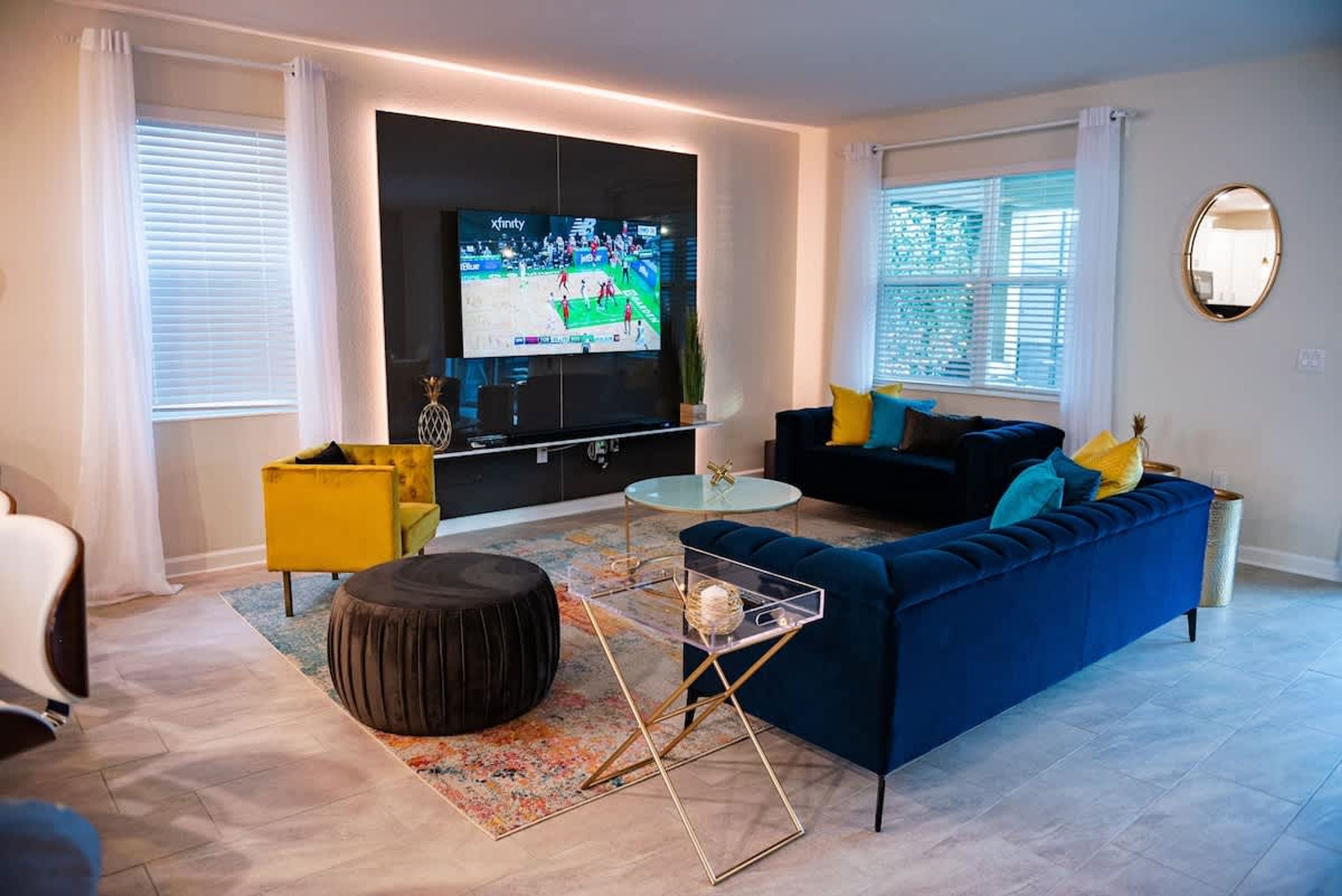 A modern living room with a blue sofa, yellow armchair, and a glass coffee table.