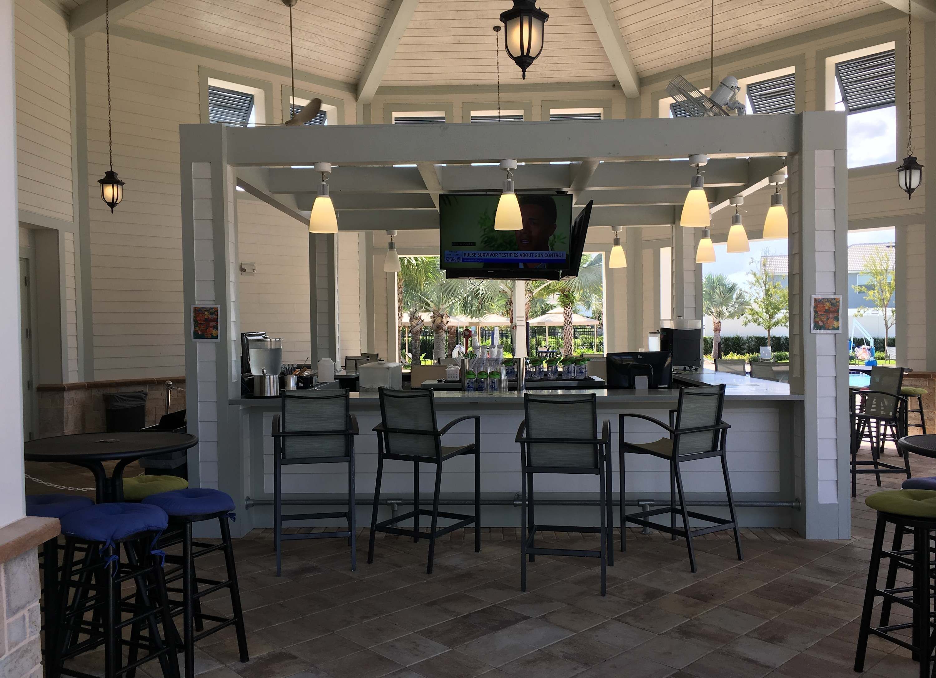 A bar area with a TV screen, multiple chairs, and a counter.