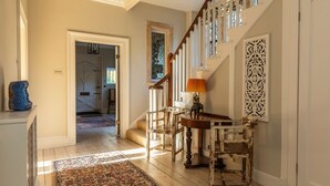 A hallway with a wooden staircase, a patterned rug, and a table with a lamp. - Georgian House With Garden Views Tennis Court (Bath)