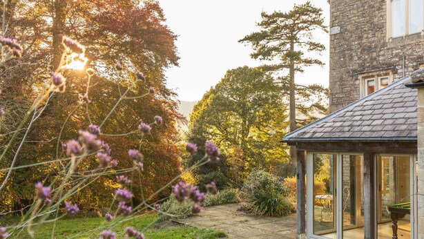 A stone building with a glass conservatory and a garden with trees and shrubs. - Georgian House With Garden Views Tennis Court (Bath)
