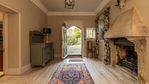 A hallway with a patterned rug, a fireplace, and a door leading to an outdoor area. - Georgian House With Garden Views Tennis Court (Bath)