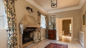 A room with a fireplace, patterned curtains, a wooden cabinet, and a door leading to another room. - Georgian House With Garden Views Tennis Court (Bath)