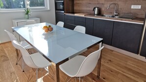 A modern kitchen with dark cabinets, a wooden countertop, and a built-in oven. - Apartments Egis Koper (Koper)