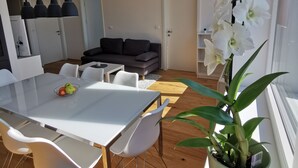 A modern living space with a dining area, a sofa, and a potted orchid. - Apartments Egis Koper (Koper)