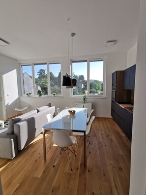 Eine moderne Küche mit Essbereich, großen Fenstern und Blick ins Grüne.