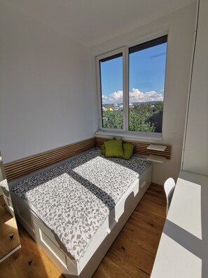 Ein Schlafzimmer mit einem Bett, einem Fenster und Blickrichtung nach außen.
