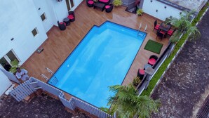 Ein Freibad mit Holzterrasse, umgeben von Gartenmöbeln und Topfpflanzen.