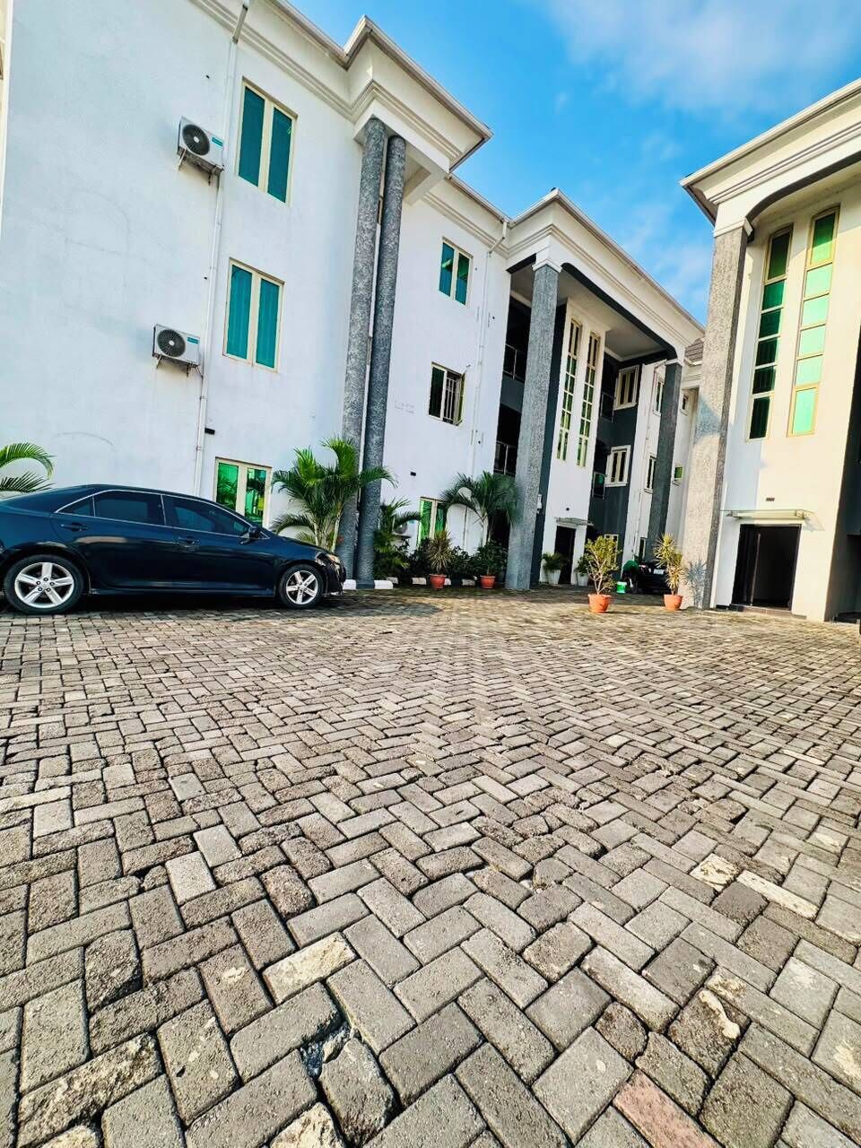 A building with a paved courtyard, air conditioning units, and potted plants.