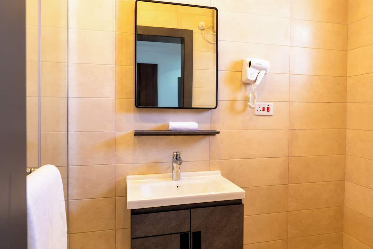 Ein Badezimmer mit Waschbecken, Spiegel und Föhn.