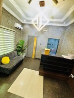 A reception area with a sofa, a plant, a desk, and a door.
