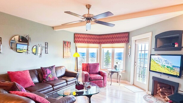 A living room with a brown leather sofa, a red armchair, a glass coffee table, and a fireplace.