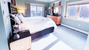 A bedroom with a bed, dresser, and a window with a view.
