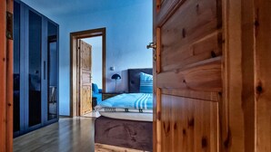 A bedroom with a bed, a nightstand, a lamp, and a wooden wardrobe.