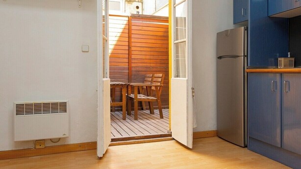 Une cuisine compacte comprenant un réfrigérateur, une table en bois avec des chaises et une petite fenêtre.