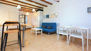 Un salon moderne avec un canapé bleu, des chaises blanches, une petite table blanche et une chaise en bois.