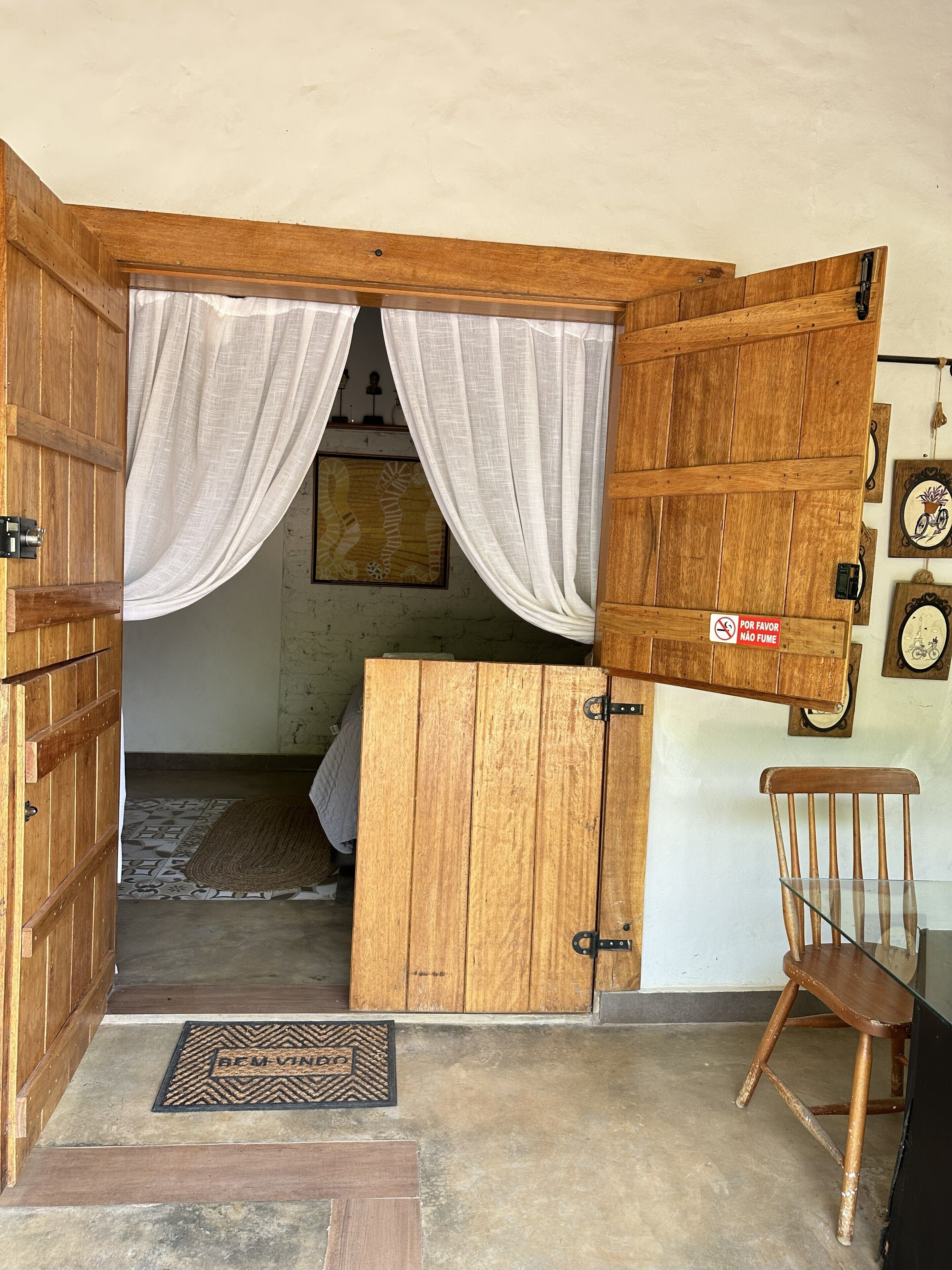 Ein rustikaler Holzraum mit einem Bett, einem Stuhl und einer Tür zu einem weiteren Zimmer.