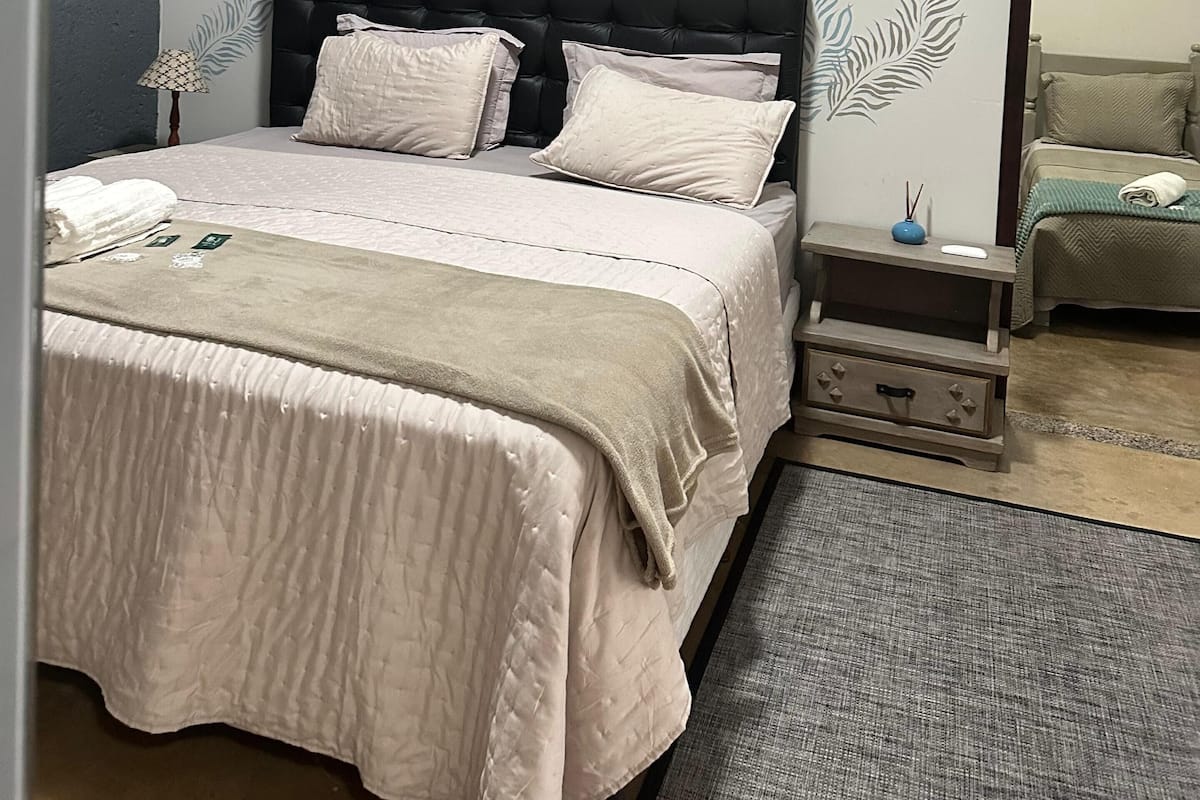 A bedroom with a bed, nightstands, and a mirror.