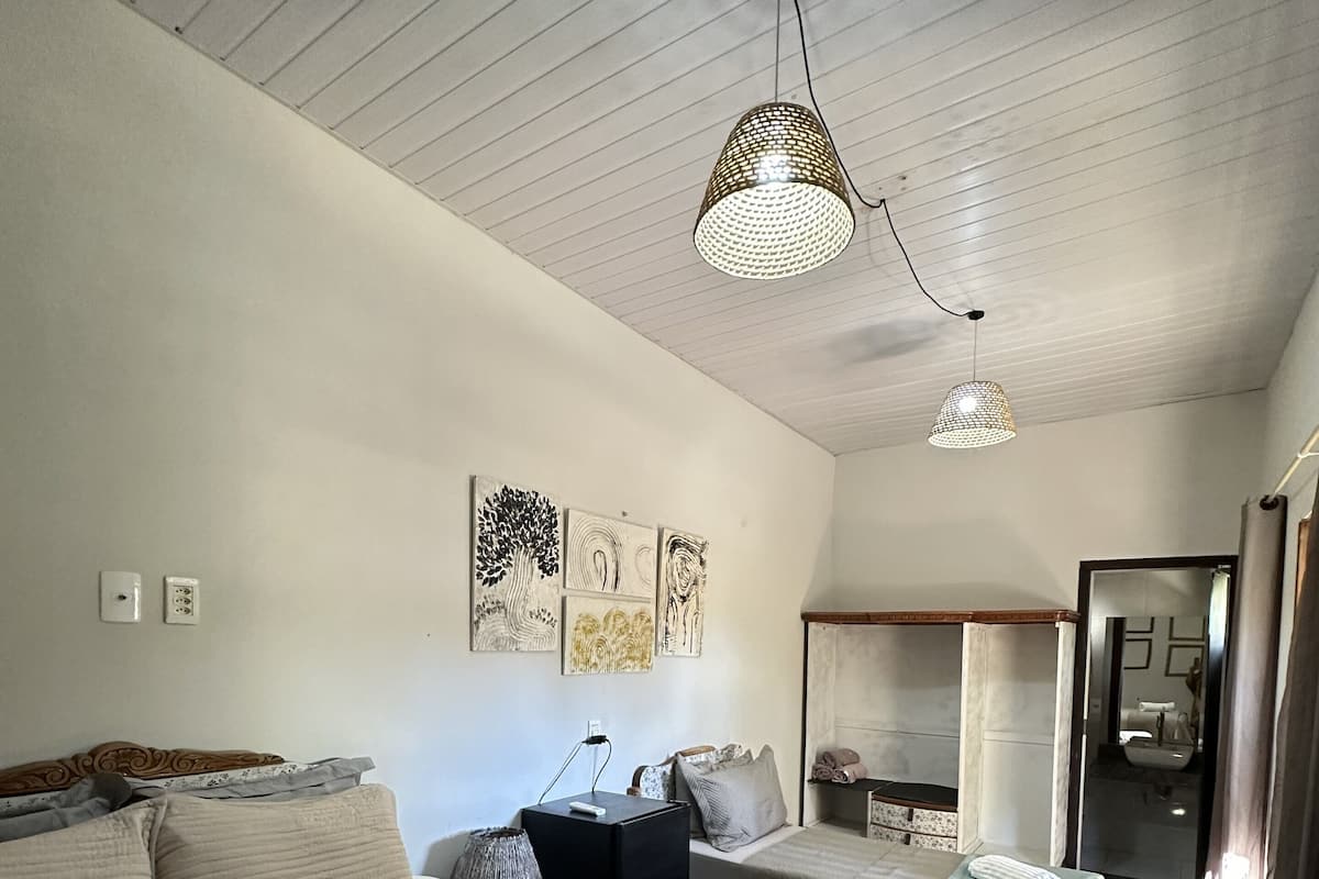A hotel room with two beds, a sitting area, artwork on the wall, and a bathroom visible through an open door.