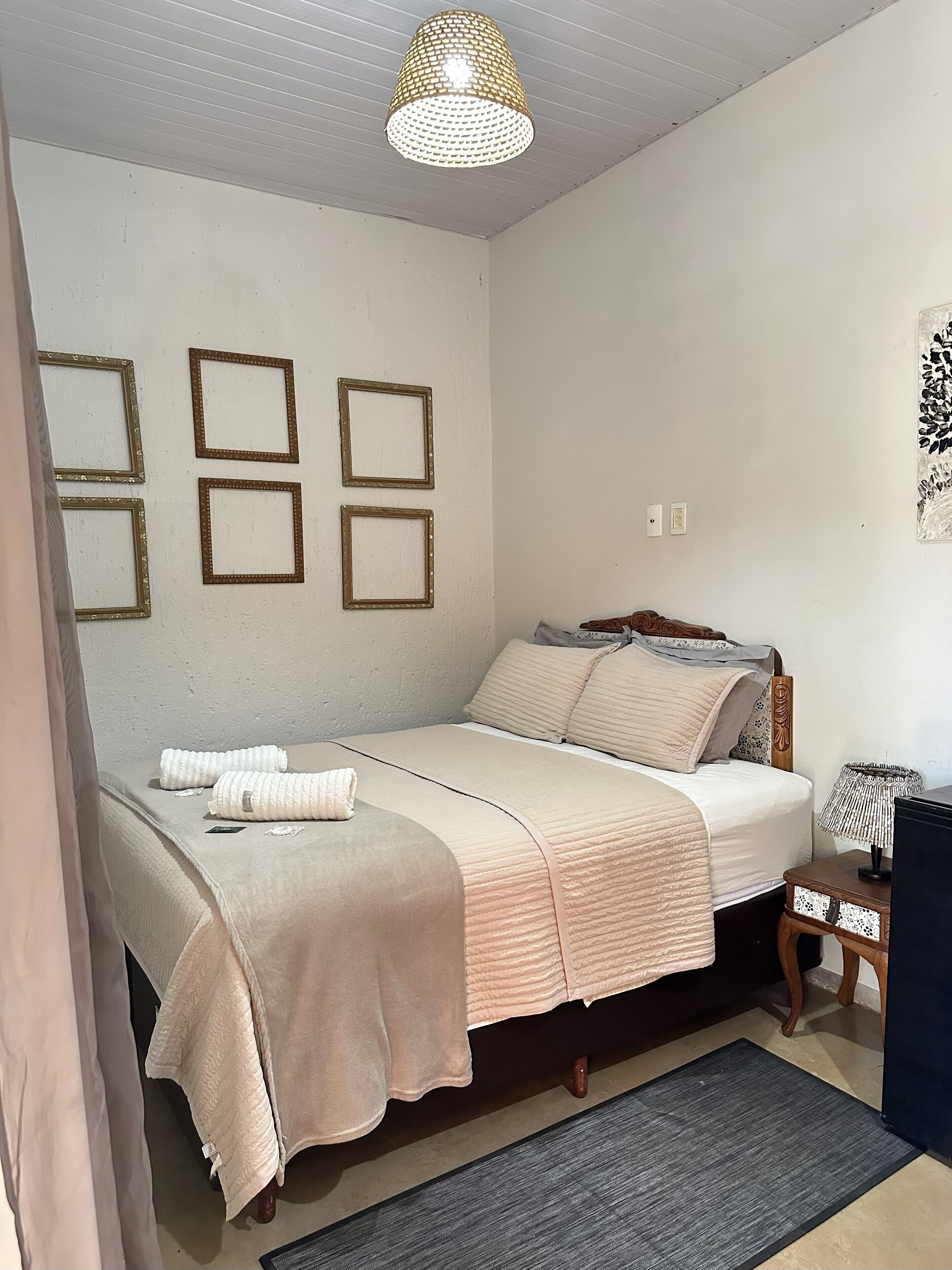 A bedroom with a bed, a bedside table, a lamp, and a ceiling light fixture.