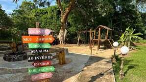 Un segnale direzionale in legno con diverse indicazioni, immerso in un giardino.