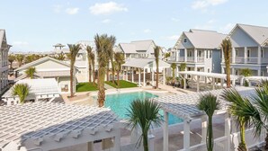 A resort with a swimming pool, white buildings, and palm trees.