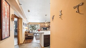A hallway leading to a living area with a fireplace, a dining area, and a kitchen with stone accents. - Atrium 005: Historic District Ski Condo, Fireplace, Hot Tub Access. (Breckenridge)