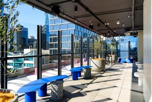A modern rooftop terrace with large windows, blue seating, and potted plants. - Student Only Victoria Market (Melbourne)