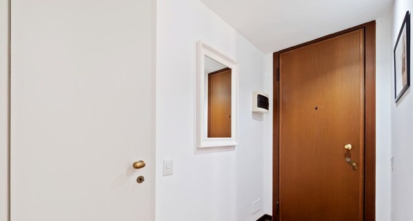 Un couloir avec une porte en bois, une petite fenêtre et un climatiseur fixé au mur.