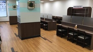 Un espacio de oficina moderno con cubículos, suelo de madera y un letrero que indica devolución de bandejas.