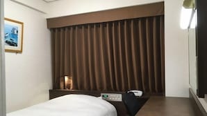 Habitación de hotel con cama, escritorio, silla, lámpara y un cuadro en la pared.