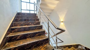 Un escalier en marbre avec des rampes en métal et un luminaire fixé au mur.